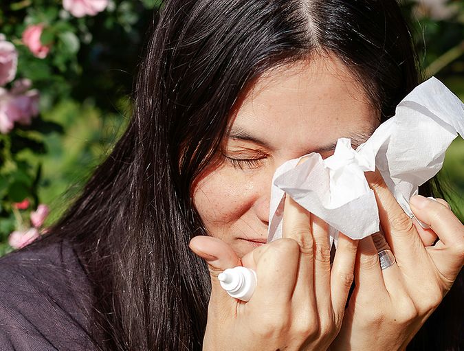 Woman dries eyes with tissue after applying eye drops